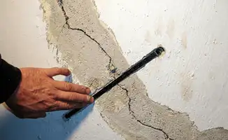 A wall with a large crack is being inspected by a professional in Atlanta, GA